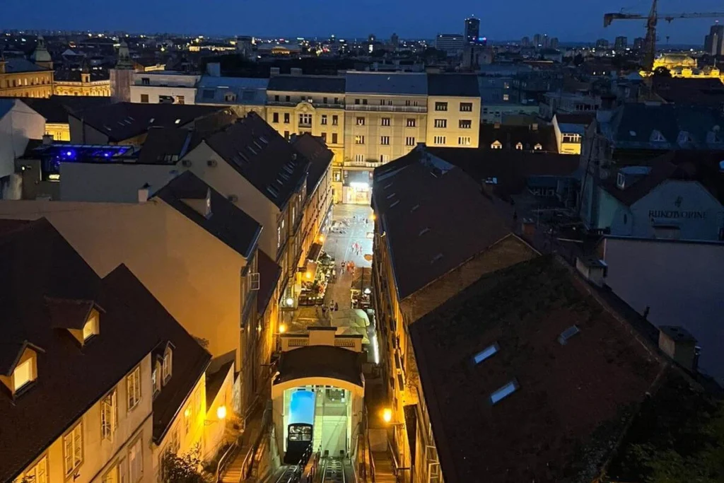 View from the top of the Zagreb Funicular overlooking the illuminated Tomićeva street and Lower Town city lights at night.