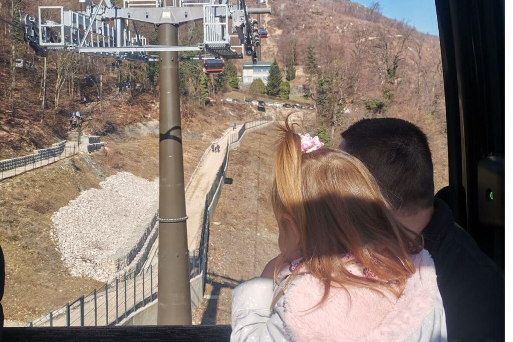 A father and young child looking out the window of the Sljeme Cable Car at the mountain landscape in Zagreb, Croatia.
