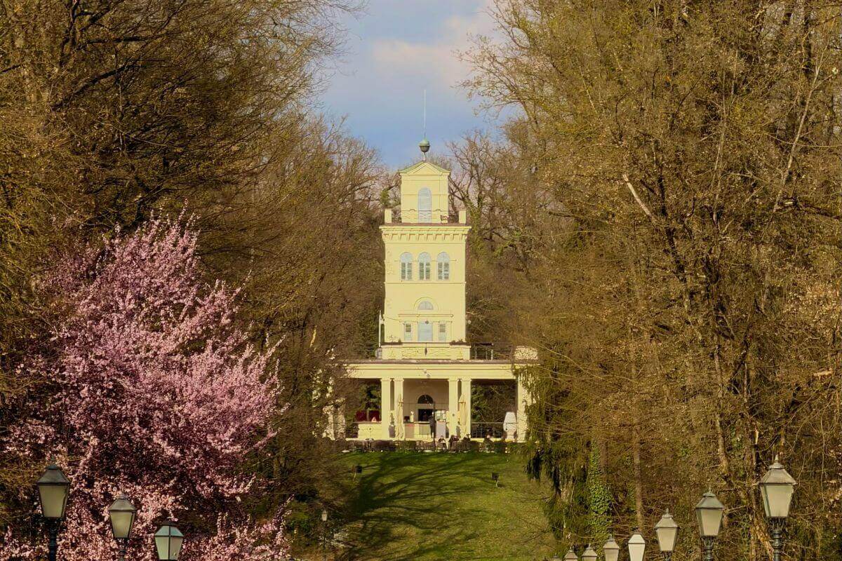 The yellow Vidikovac observation deck tower at Maksimir Park in Zagreb, surrounded by spring trees and pink blossoms.