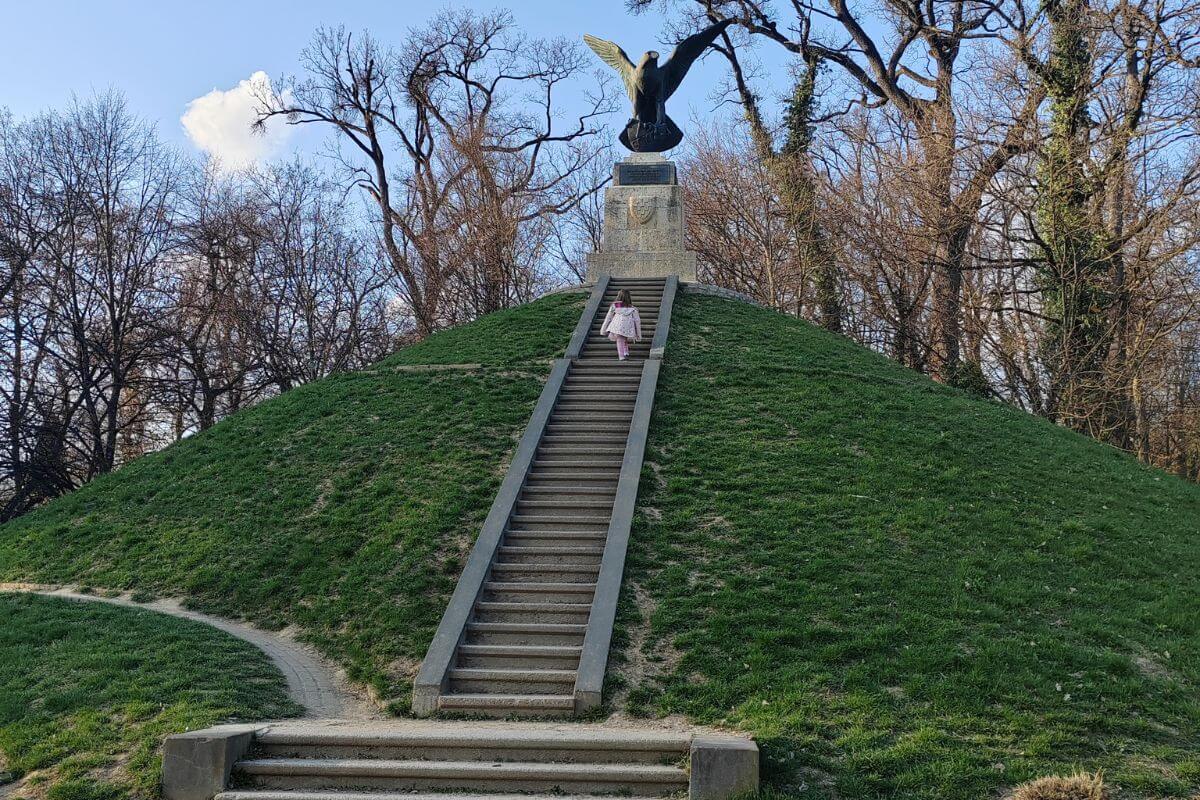 A child walking up a long flight of stone stairs leading to the top of the grassy Mogila mound.