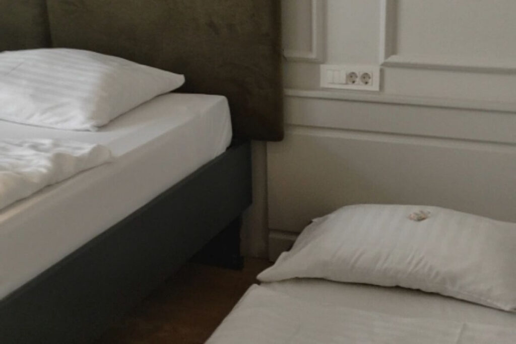 A main double bed next to a low single extra bed setup on the floor for a child.