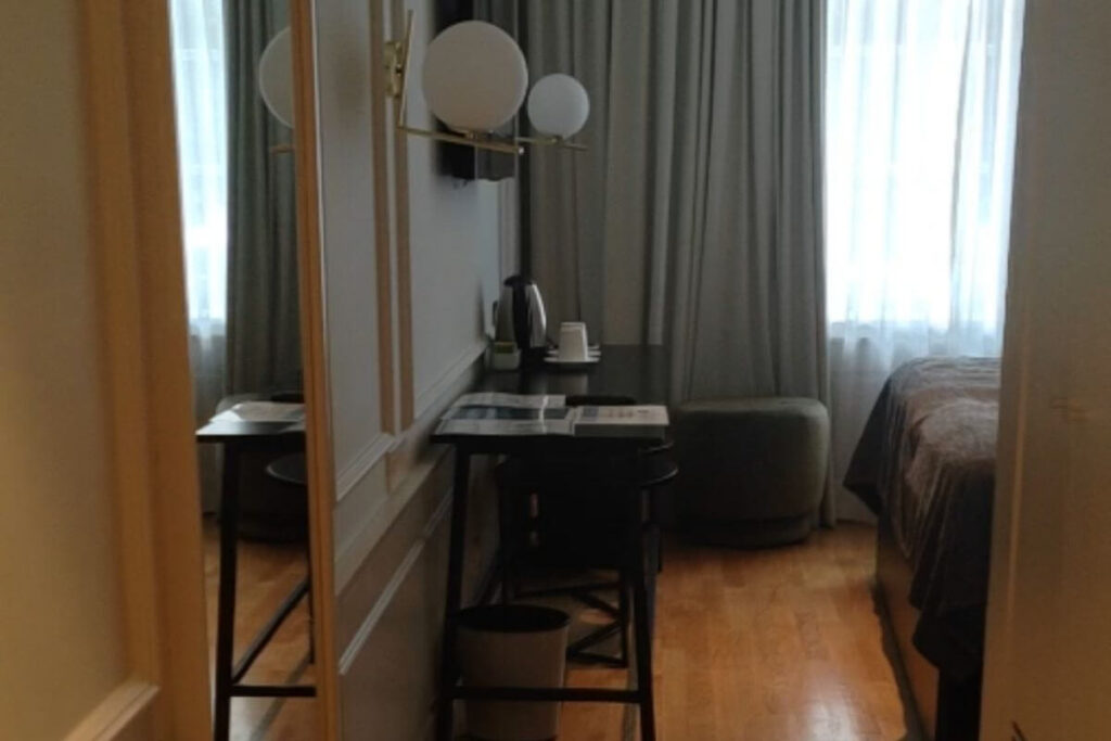 The entrance hallway of a hotel room at Family Hotel Lišanj showing a wood floor, large mirror, and desk setup.