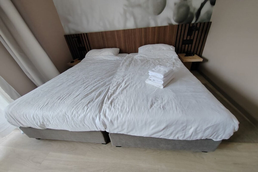 Large double bed with crisp white linens and folded towels in a modern hotel room at Hotel Garden Istra Plava Laguna.