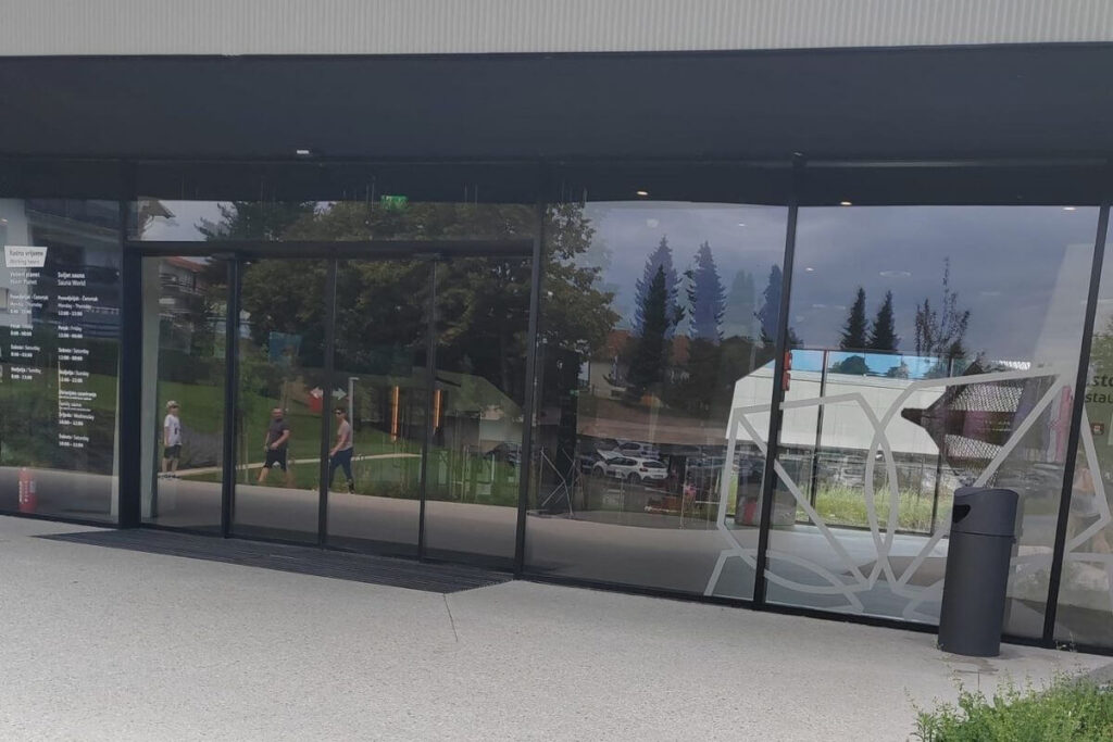 Glass entrance doors at Terme Tuhelj with printed opening hours and reception signage.