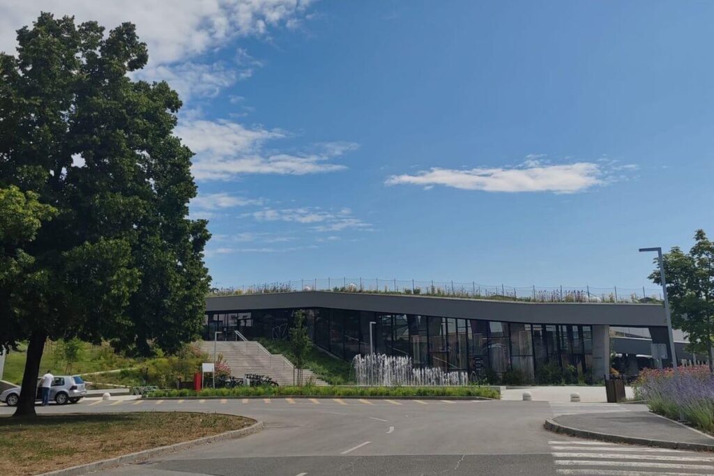 Exterior view of Terme Tuhelj building with outdoor stairs, fountains, and green roof architecture.