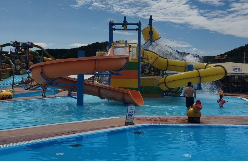 Multiple winding water slides emptying into an outdoor splash pool at Terme Tuhelj.