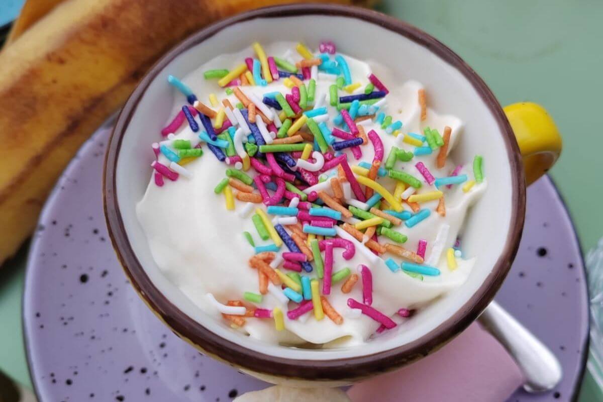 A small cup of foamed milk topped with rainbow sprinkles served at a family-friendly cafe in Zagreb, Croatia