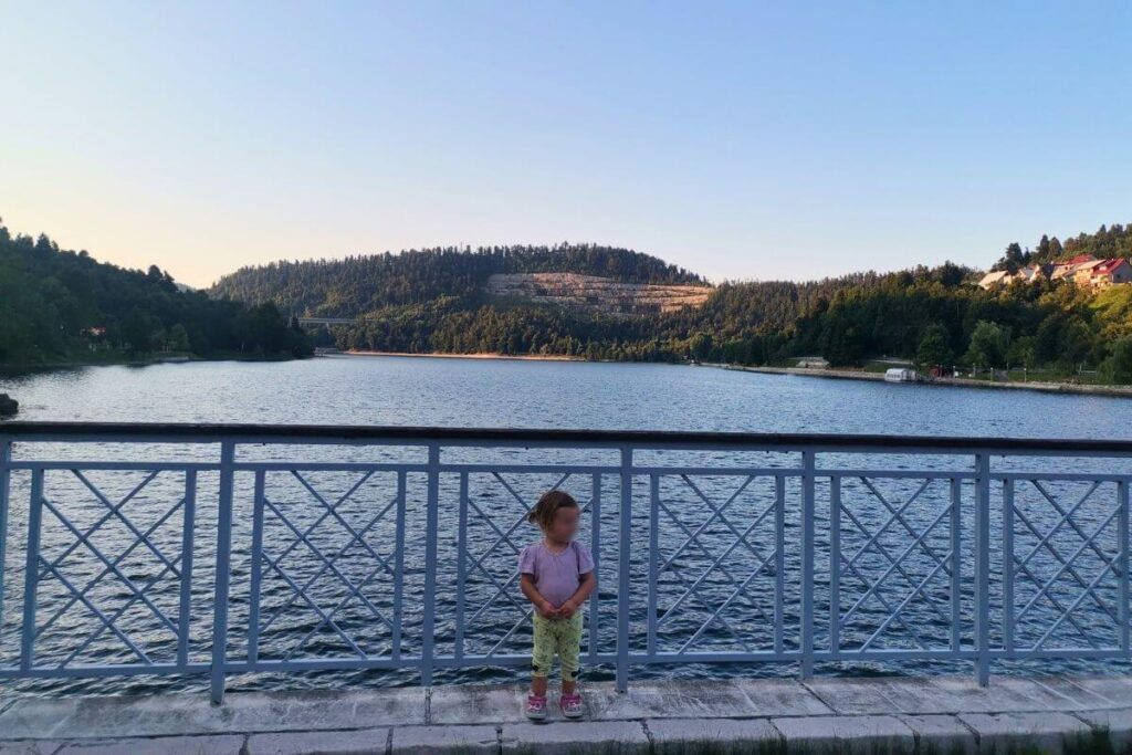 Young girl standing at the wooden railing overlooking Lake Bajer in Fuzine Gorski Kotar
