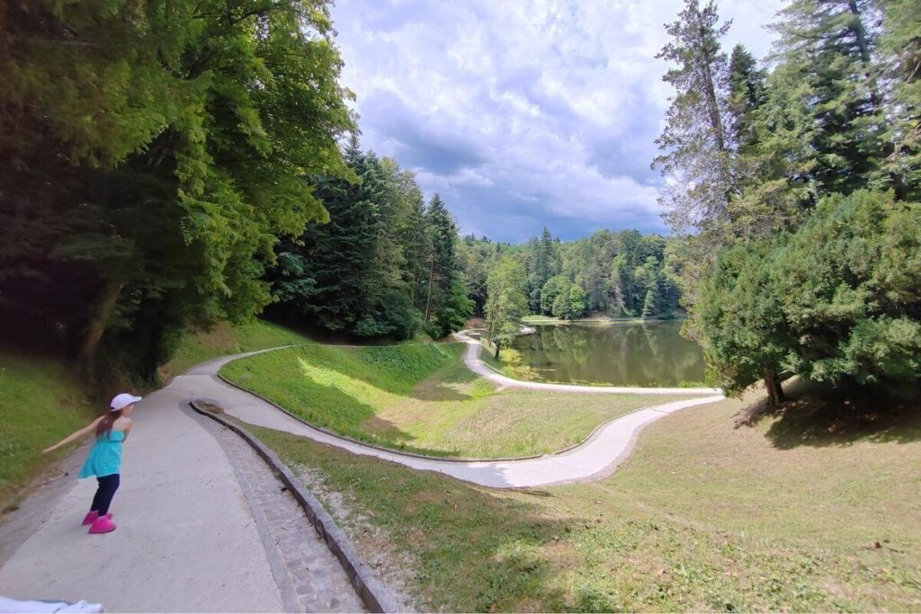 Young girl running along the paved walking trail around the forest lake at Trakoscan Castle